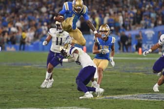 UCLA Bruins Stage Just Right for Utah Utes Act 8 UCLA Quarterback Dorian Thompson-Robinson Hurdles Washington Huskies Defender. Photo Credit: Greg Turk | UCLA Athletics