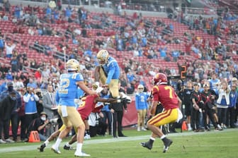 UCLA Football: UCLA Quarterback Dorian Thompson-Robinson Hurdles A USC Defender. Photo Credit: Jesus Ramirez | UCLA Athletics