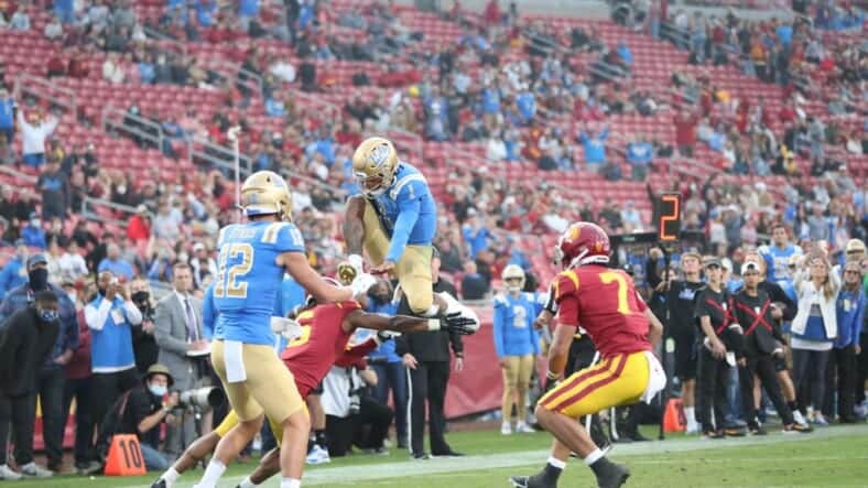 UCLA Football: UCLA Quarterback Dorian Thompson-Robinson Hurdles A USC Defender. Photo Credit: Jesus Ramirez | UCLA Athletics
