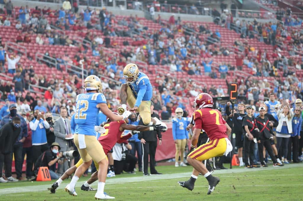 UCLA Football: UCLA Quarterback Dorian Thompson-Robinson Hurdles A USC Defender. Photo Credit: Jesus Ramirez | UCLA Athletics