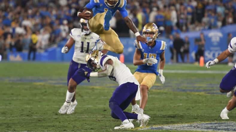 UCLA Quarterback Dorian Thompson-Robinson Hurdles Washington Huskies Defender. Photo Credit: Greg Turk | UCLA Athletics